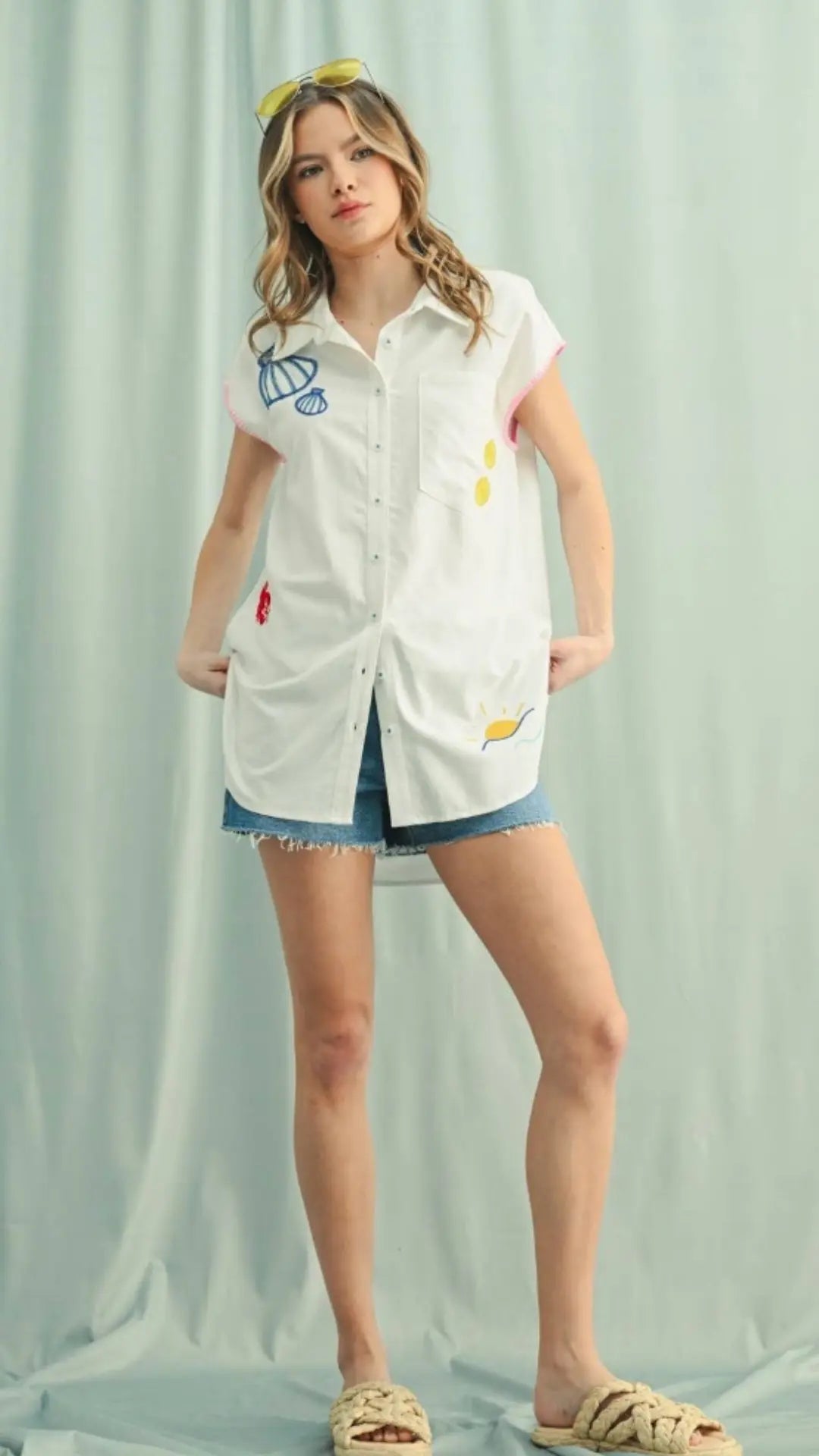 Model wearing oversized white embroidered tunic with denim shorts